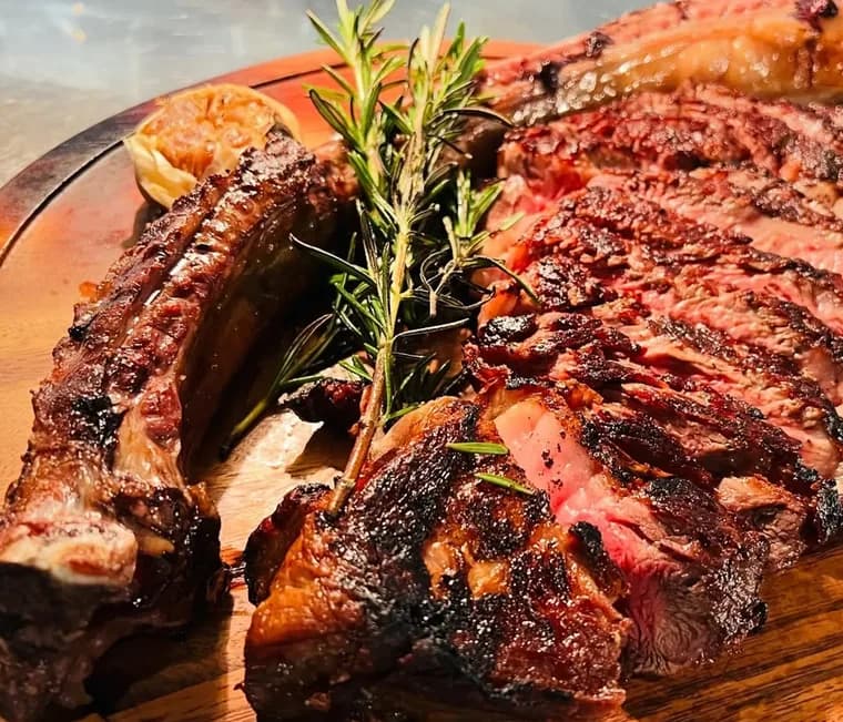 Sliced dry-aged Tomahawk steak on a wooden board